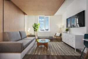 Stylish flexible ORI studio living room with raised Murphy bed at 88 East 127th Street apartments in Harlem NYC.